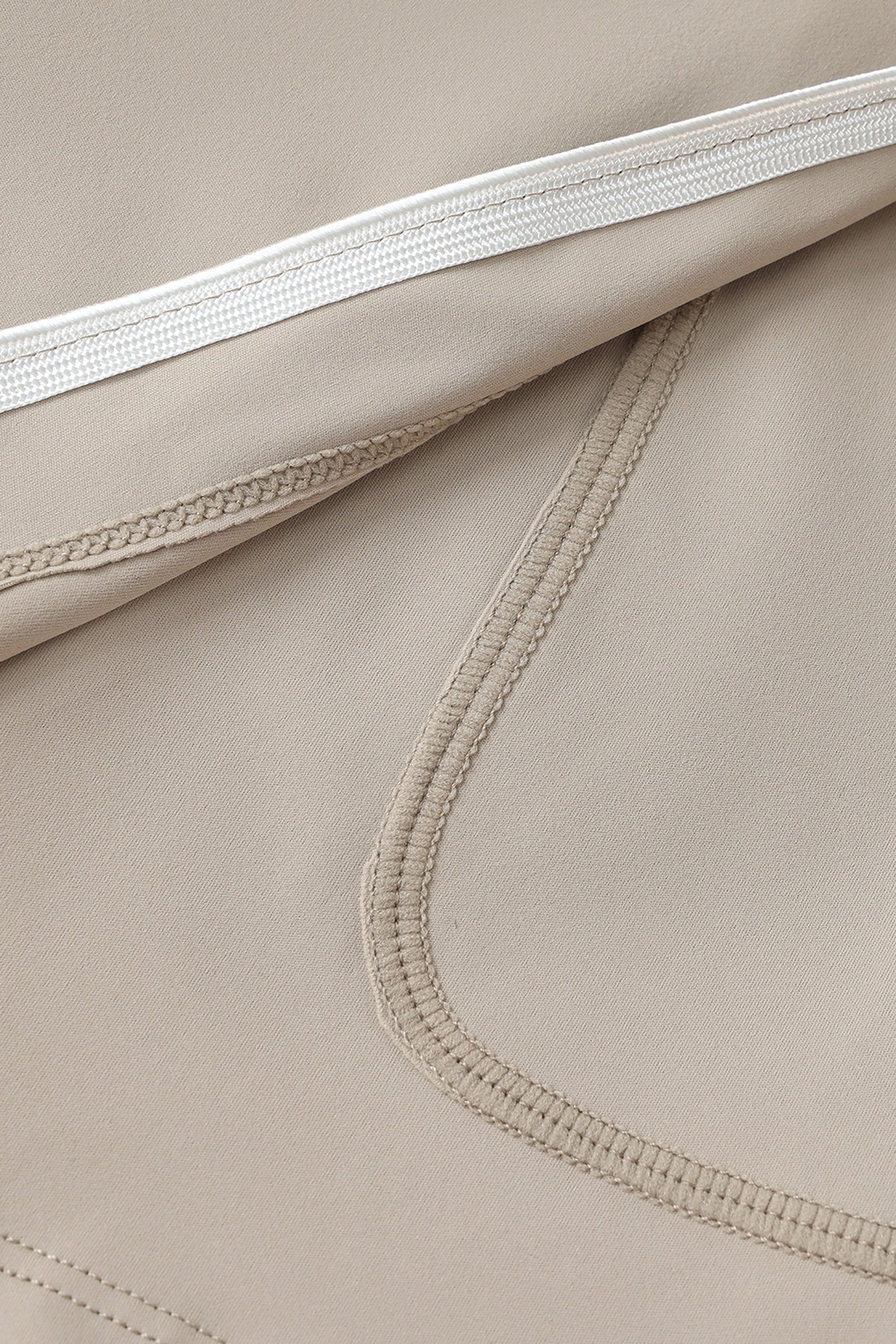 Close-up of beige fabric with white hem and stitching details