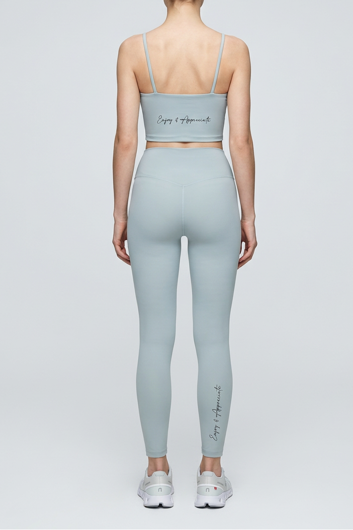 Person wearing a light gray sports bra and leggings set on a white background