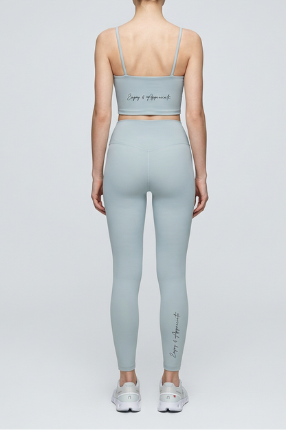 Person wearing a light gray sports bra and leggings set on a white background