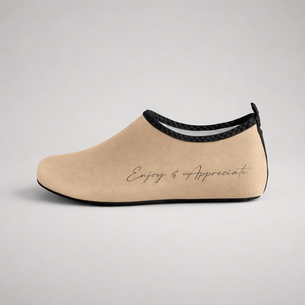 Beige suede slip-on aqua shoe with black trim and embroidered enjoy and appreciate script for barefoot intention