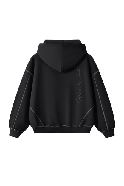 A black pullover hoodie shown from the back, featuring a subtle vertical script graphic on the right side and thin light gray piping details along the shoulders and sides, set against a plain white background.