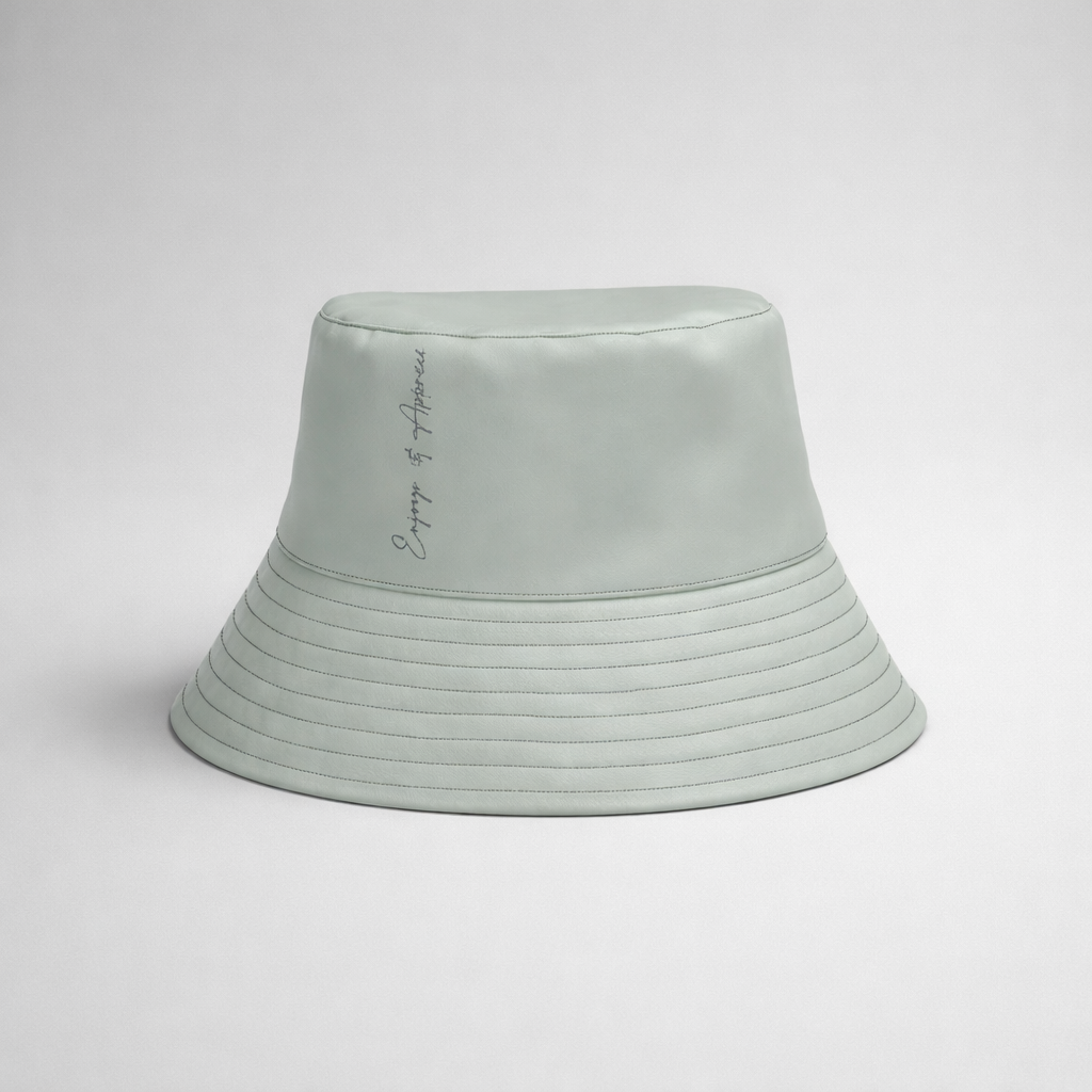 A light mint green bucket hat with subtle horizontal stitching and a delicate cursive inscription on the side