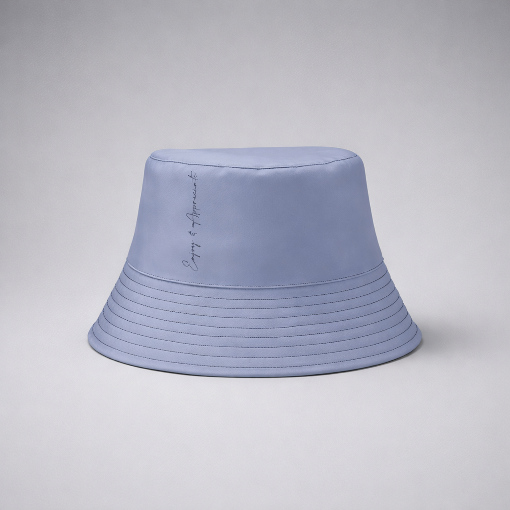 A light blue bucket hat with subtle horizontal stitching and a delicate cursive inscription on the side