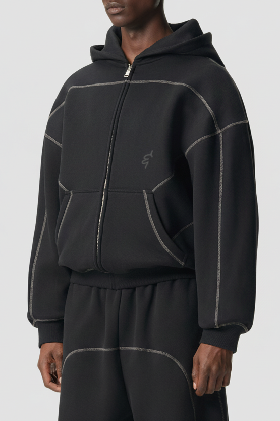 Man wearing black contrast-stitched fleece hoodie and matching wide leg sweatpants, relaxed unisex mindful activewear.