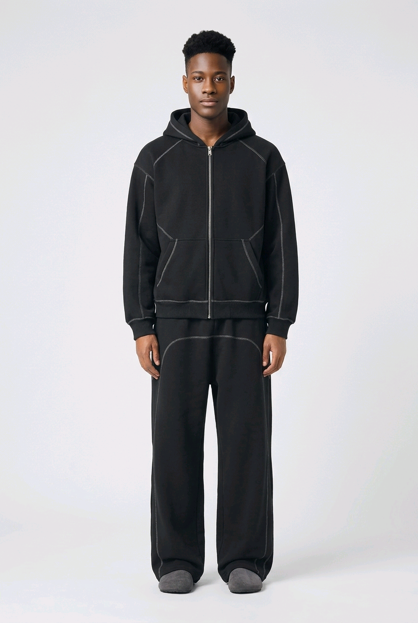 Man wearing black contrast-stitched fleece hoodie and matching wide leg sweatpants, relaxed unisex mindful activewear set styled for intentional living