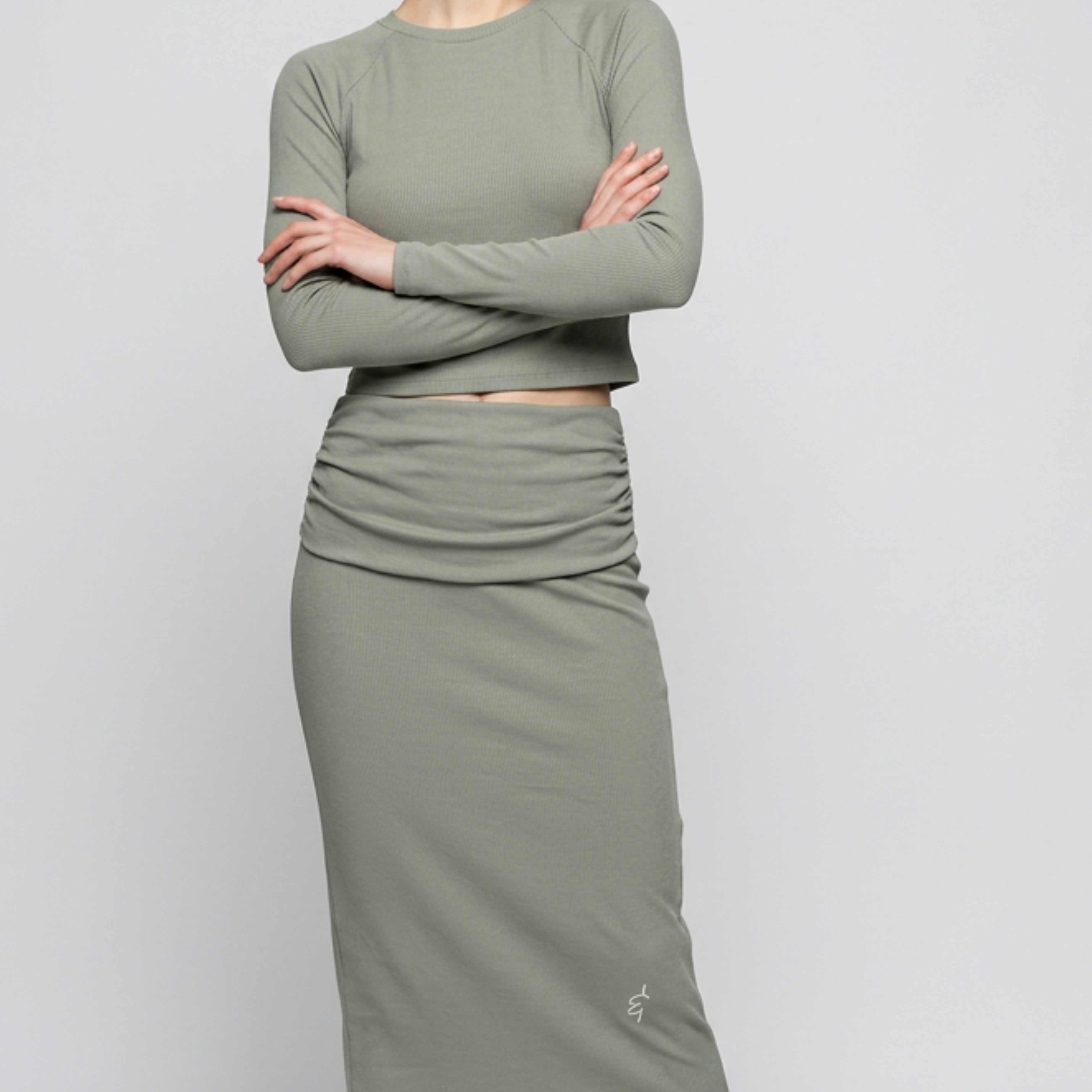 A sleek olive green long-sleeved crop top with a round neckline and subtle ruching at the waistband.
