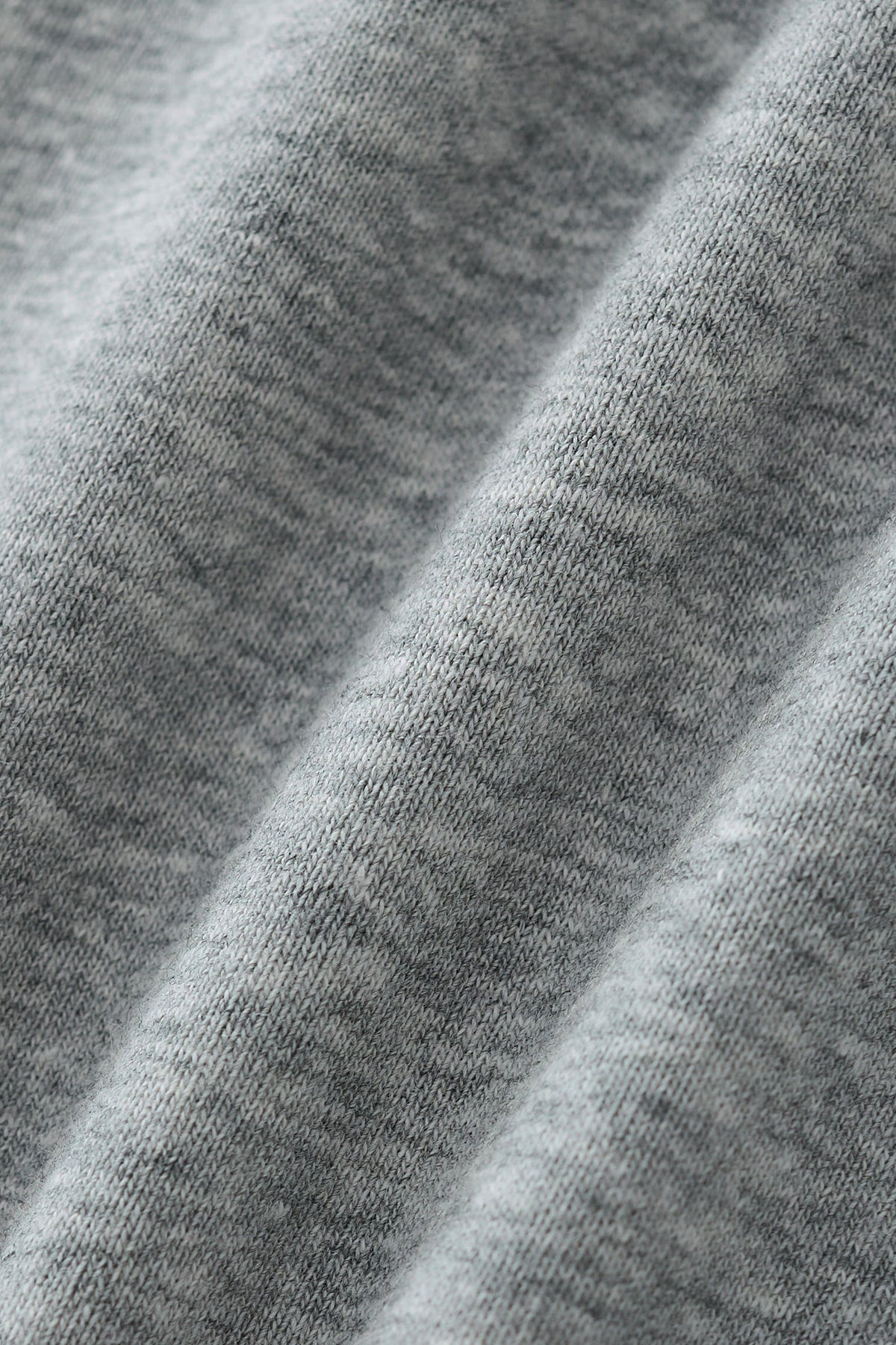 Close-up of a heather gray knit fabric with soft diagonal folds showing the texture and weave.