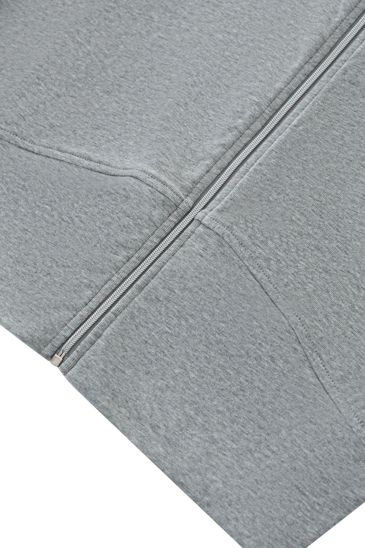 Close-up of a light gray heathered fabric garment, showing a diagonal zipper and stitched seam details against a white background.