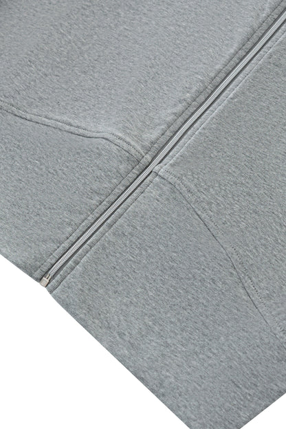 Close-up of a light gray heathered fabric garment, showing a diagonal zipper and stitched seam details against a white background.