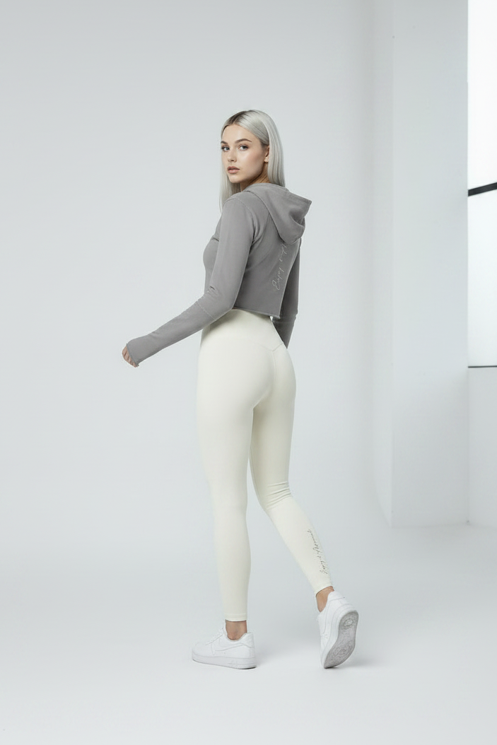 Person wearing a gray hoodie and white leggings on a light gray background