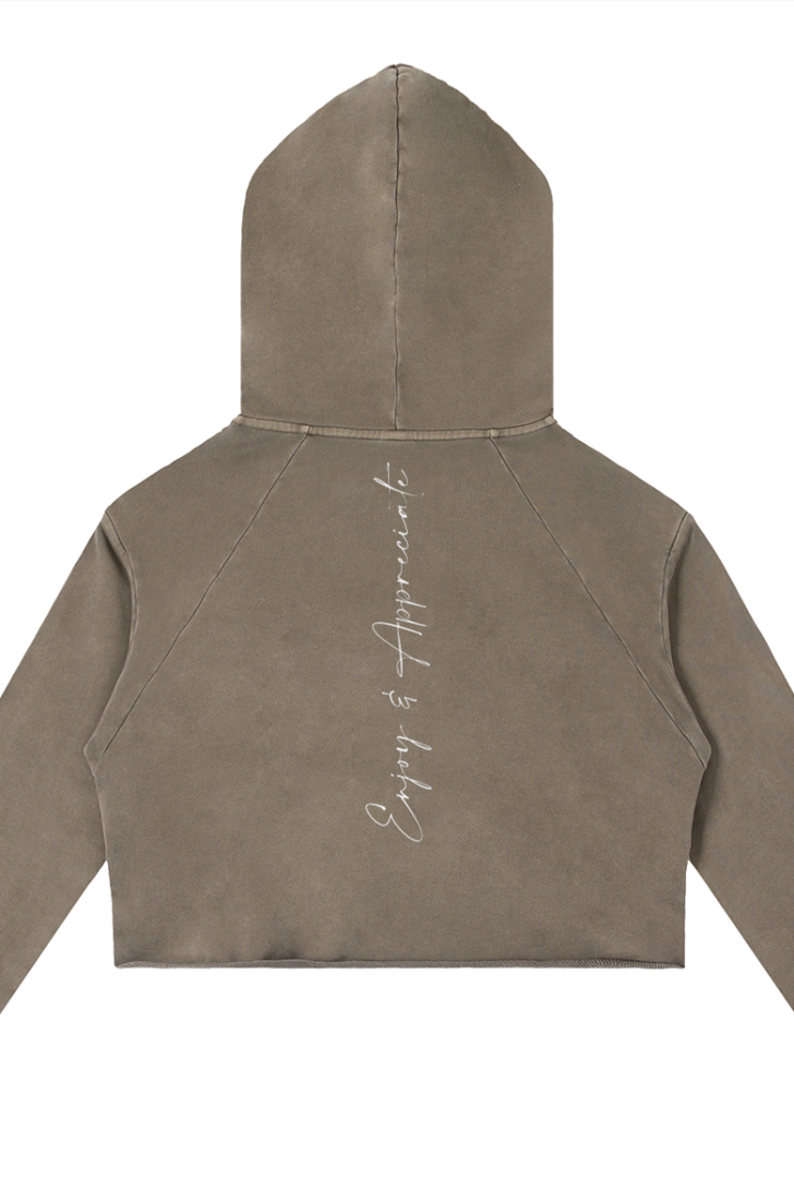 A cropped coffee colour raw edge hoodie with subtle enjoy and appreciate embroidery on the back