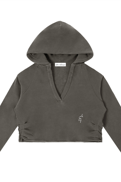 A dark olive green cropped raw edge hoodie with v-neckline long sleeves and embroidered logo on the left chest