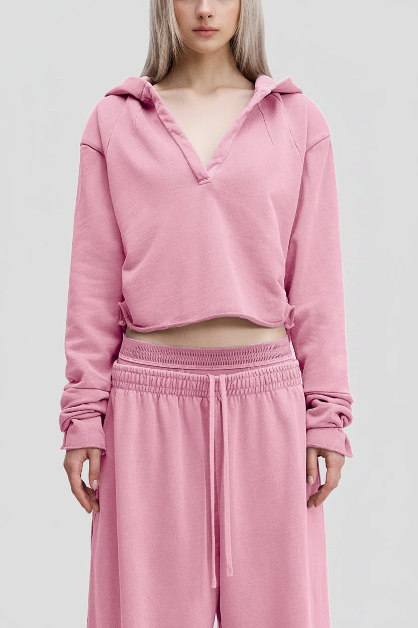 A soft pink cropped hoodie with v-neck and drawstring hood paired with matching wide-leg sweatpants