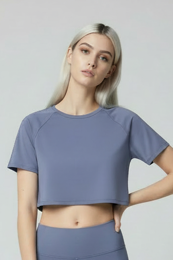 Woman wearing a purple crop top and light blue jeans on a white background