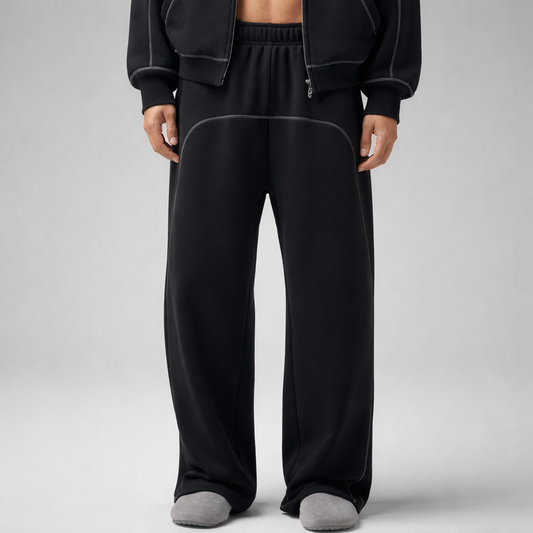 Person wearing black sweatpants with white line on a gray background