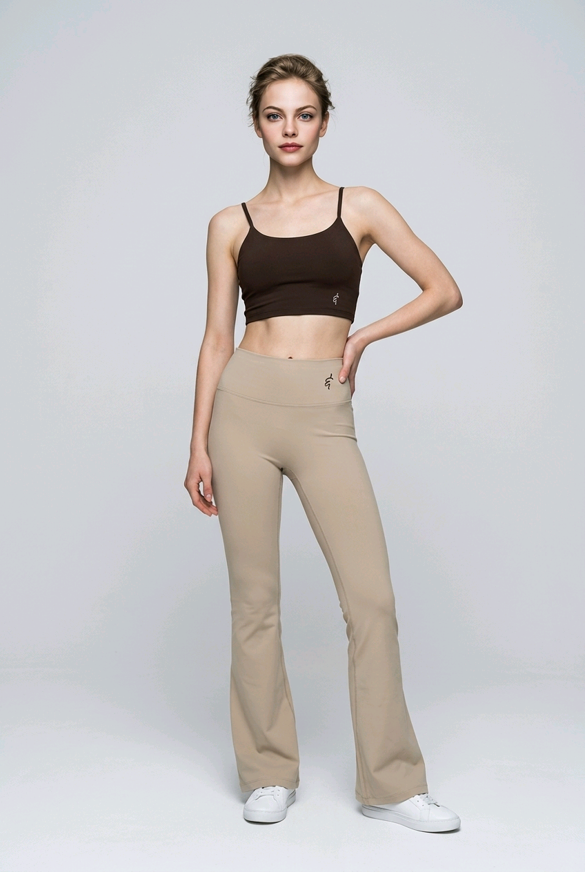 A woman wearing beige high-waisted seamless flared leggings paired with a brown sports bra and white sneakers