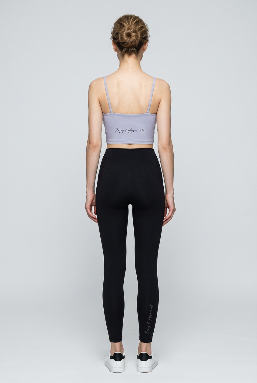 A sleek light gray sports bra with thin straps and minimalist design paired with seamless high-waisted leggings