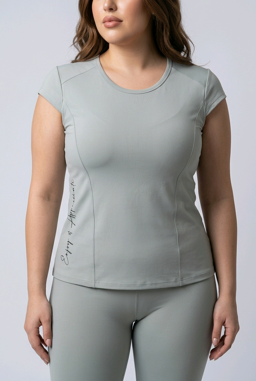 Woman wearing a light gray athletic top and leggings on a white background