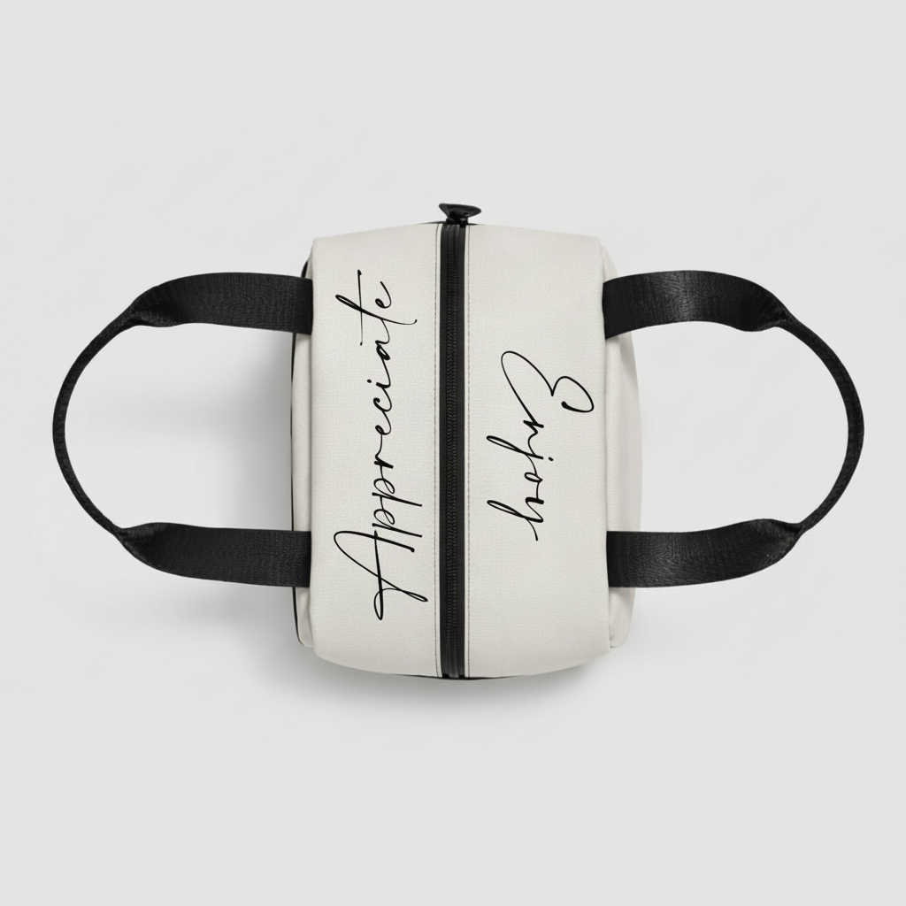 A sleek white insulated lunch bag with black handles and cursive appreciate and enjoy text for daily meals