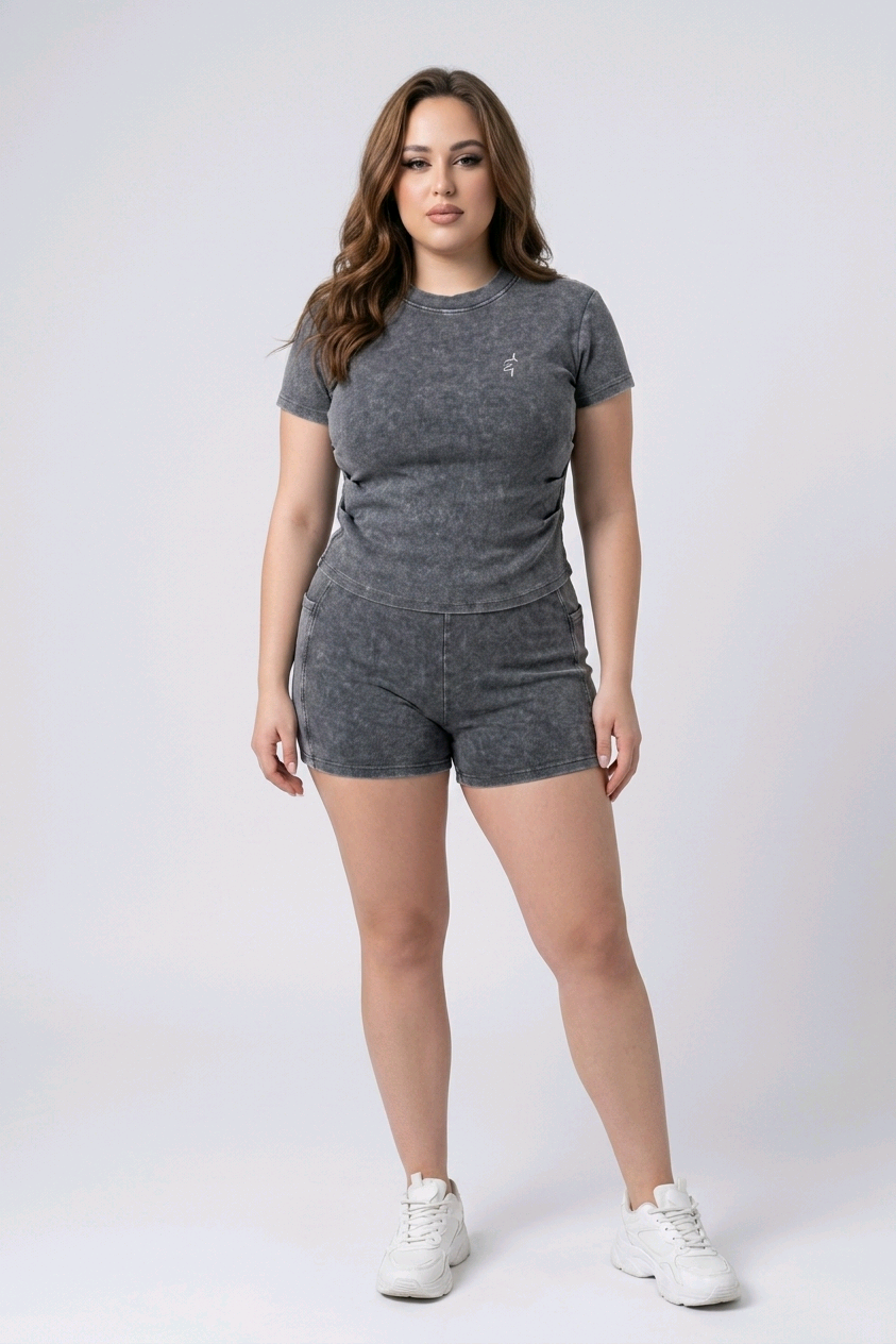 Woman wearing a gray t-shirt and shorts set with white sneakers on a white background