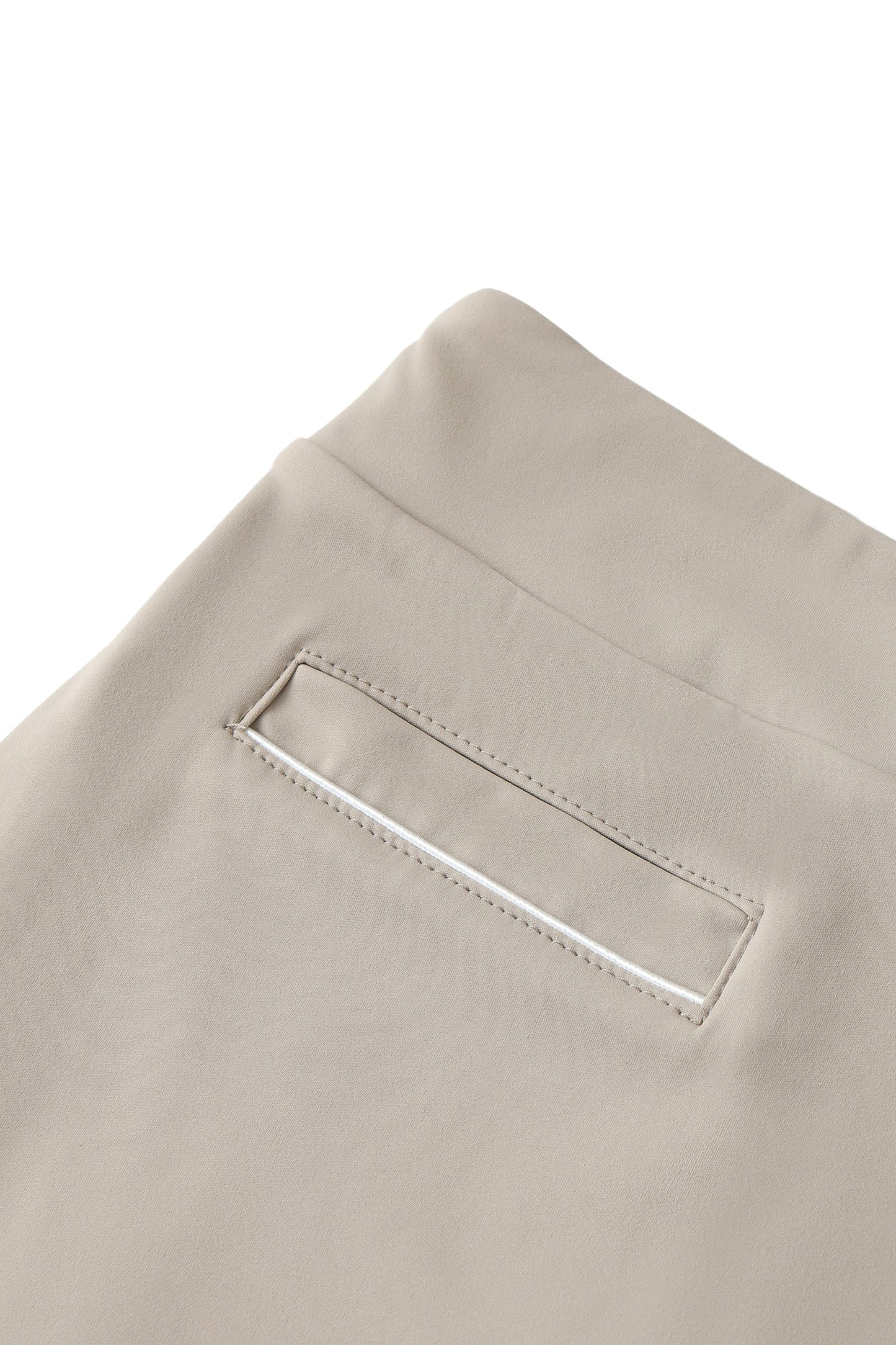 Close-up of beige pants with a pocket detail on a white background