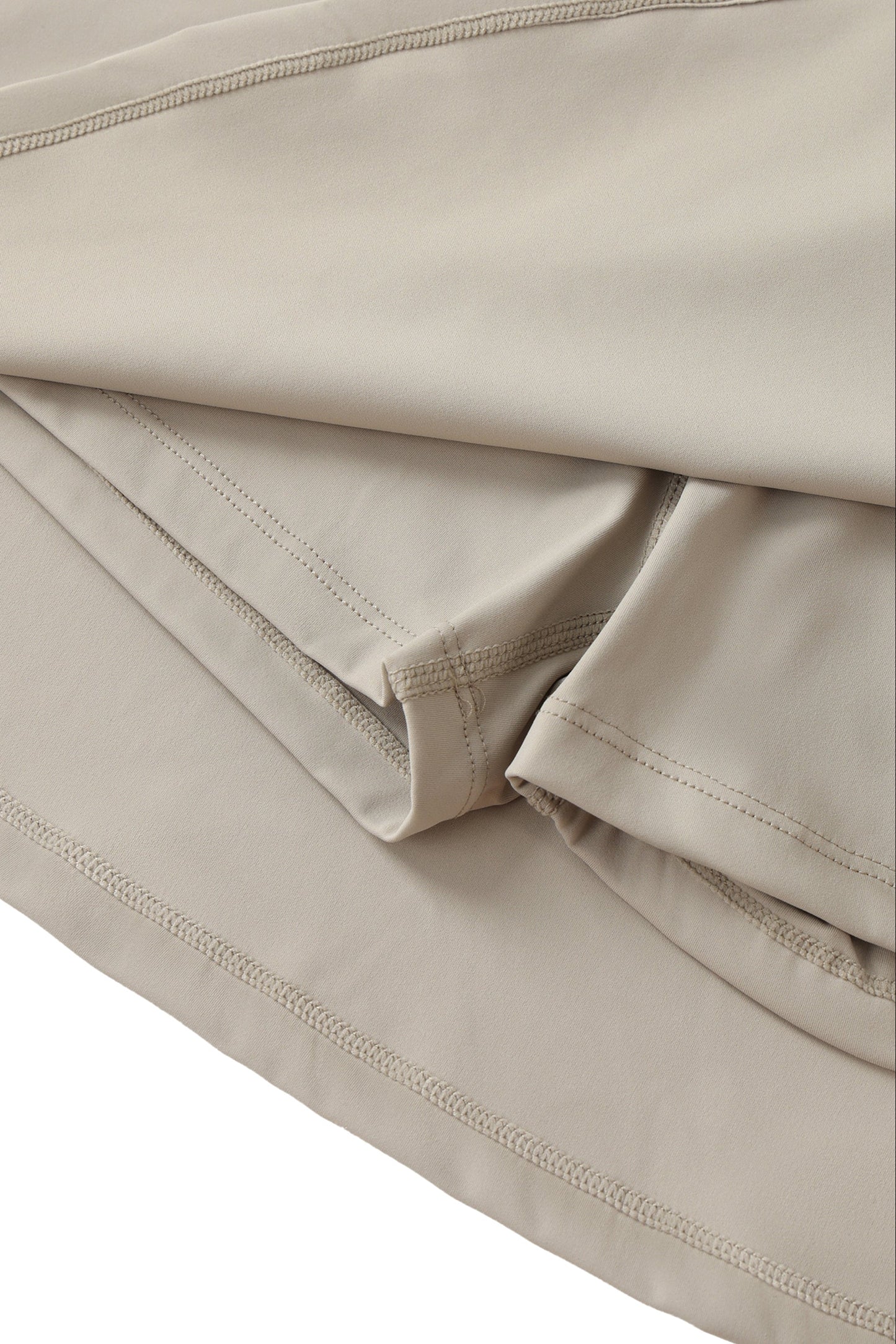 Close-up of beige skort with shorts under a skirt and with visible stitching.