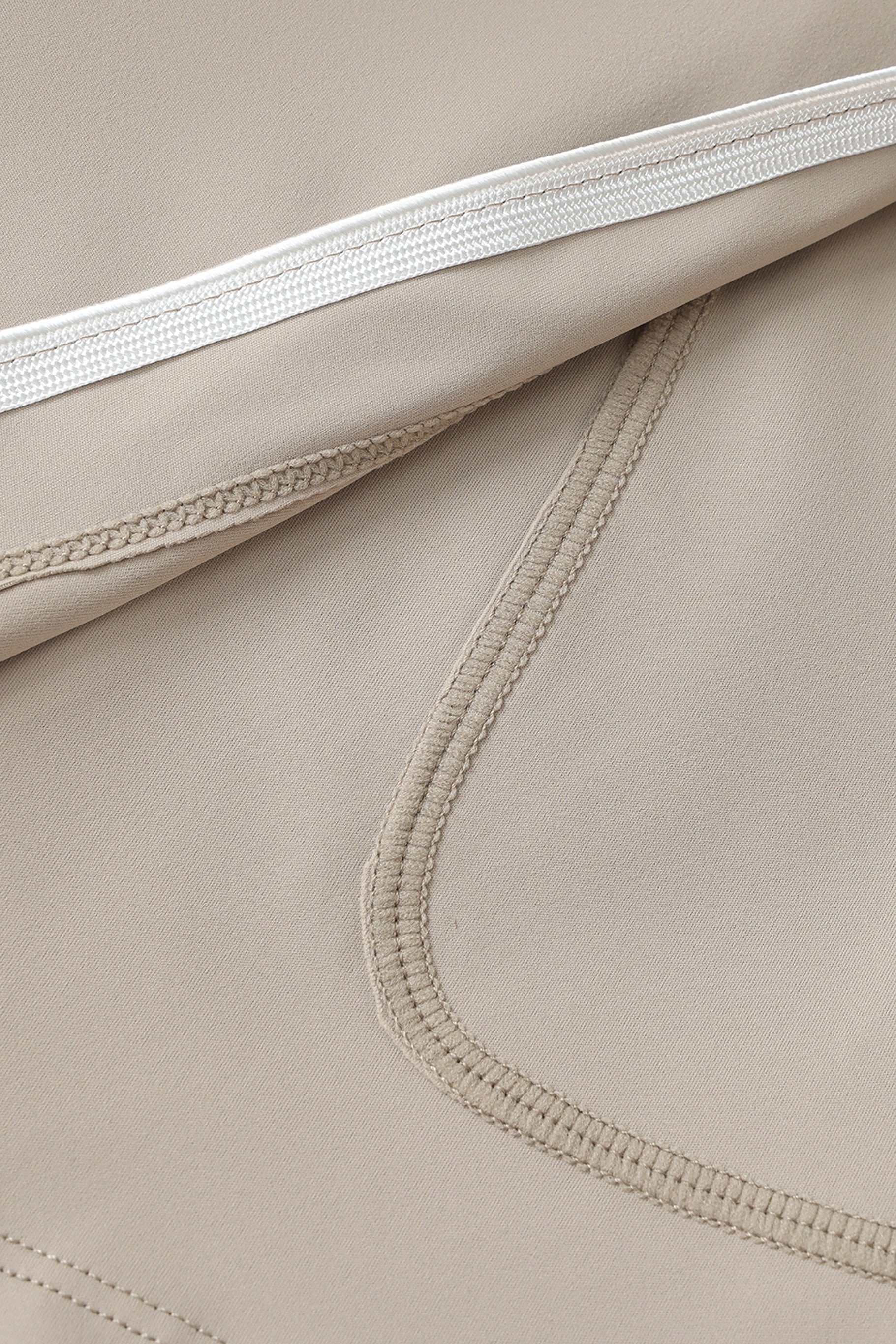 Close-up of beige fabric with white hem and stitching details