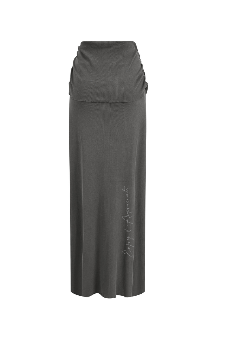 Long dark gray skirt with a fitted waistband and enjoy & appreciate text written on it on a white background
