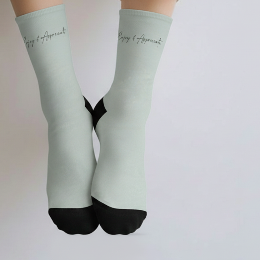 Ankle socks in light green with black toe and heel featuring enjoy and appreciate embroidered on the calf