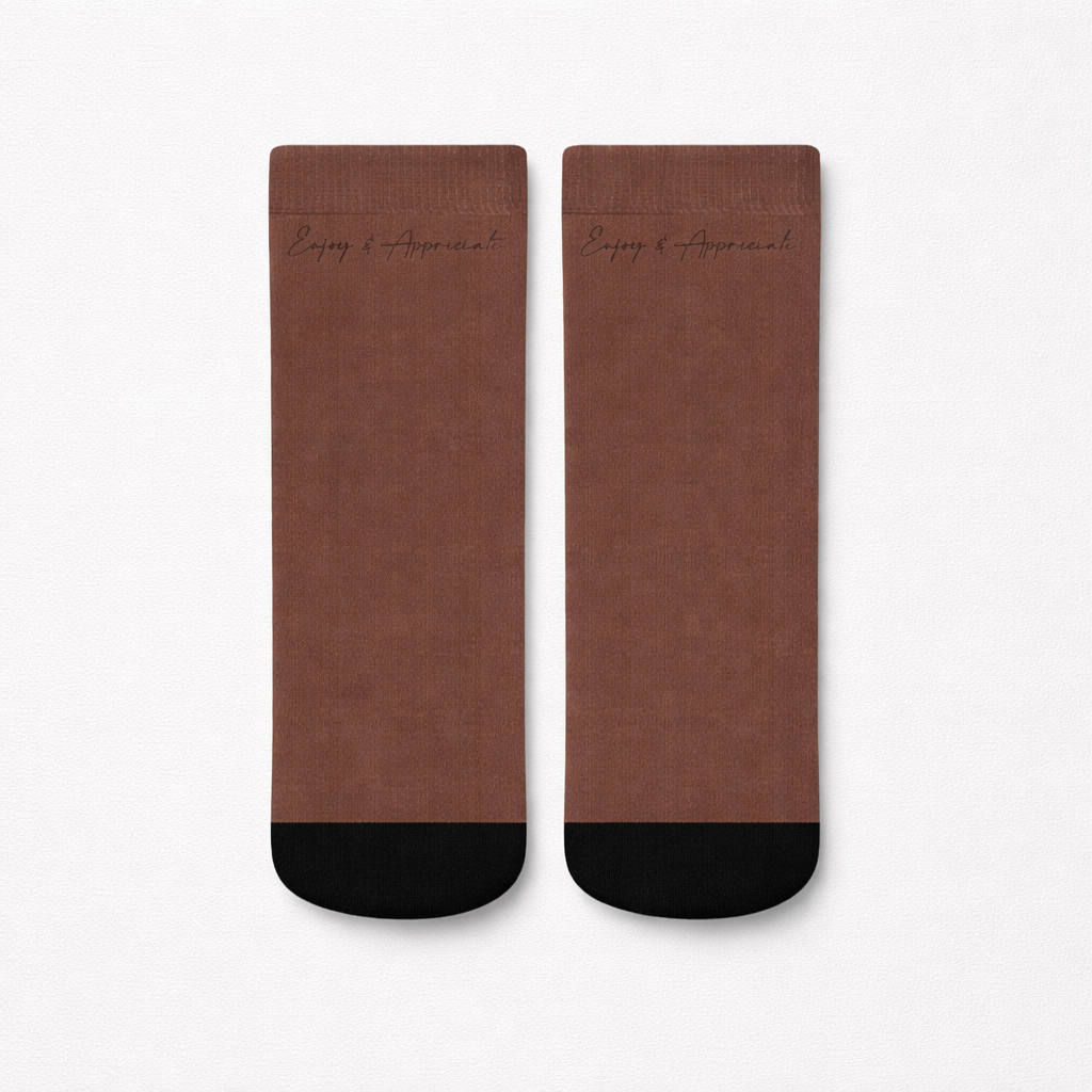 Brown leather ankle socks with black toe caps and enjoy and appreciate embossed near the top