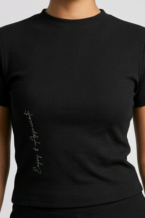 Woman wearing a black t-shirt with Enjoy & Appreciate text on a light gray background