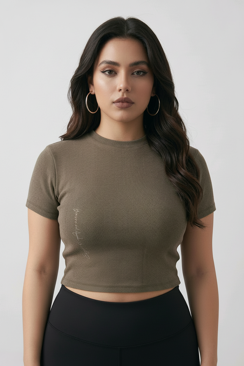 Woman wearing a brown cropped mock neck t-shirt and blue jeans against a plain background