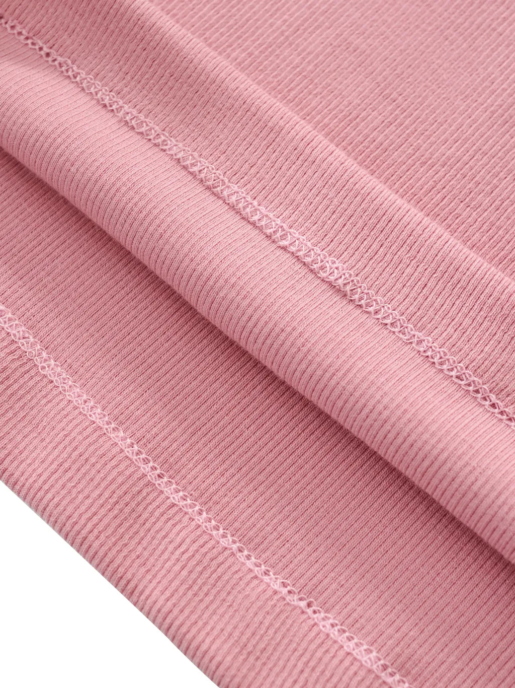 Close-up of pink ribbed fabric with visible stitching on a white background