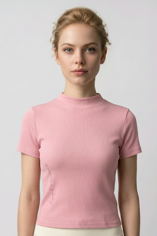Woman wearing a pink mock neck t-shirt and cream pants against a plain background