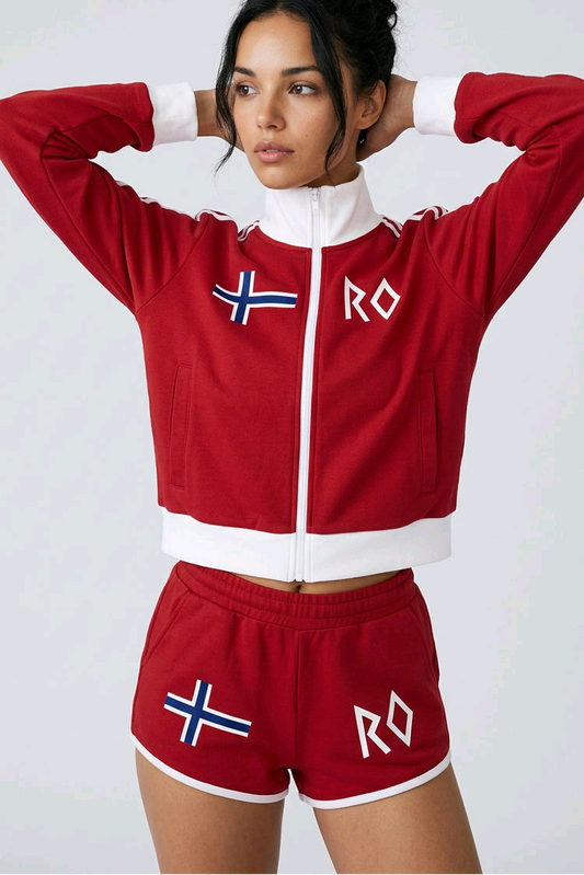 A woman modeling a red and white Norway-themed athletic tracksuit, featuring a cropped zip-up jacket with a Norwegian flag and 'NO' lettering, and matching shorts.