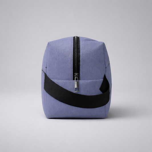 A lavender canvas sports mini toiletry bag with a black zipper and wide black strap for travel use