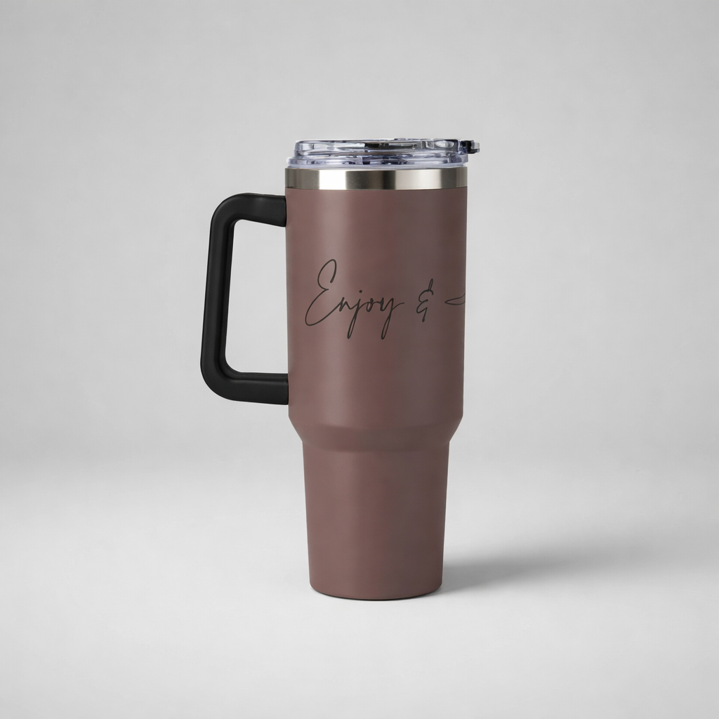 A matte brown insulated travel mug with black handle and clear lid featuring enjoy and in cursive script
