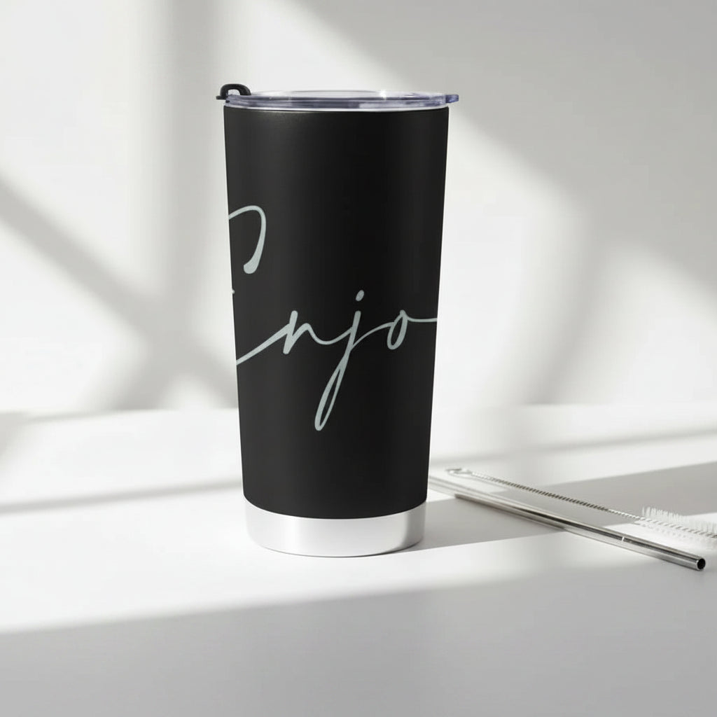 Black tumbler with 'Enjoy' text with a cleaning brush and metal straw on a light background