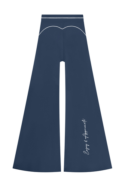 A pair of navy blue wide-leg pants with white contrast stitching, a decorative curved line near the waistband, and white script text on the lower left leg, shown against a plain white background.