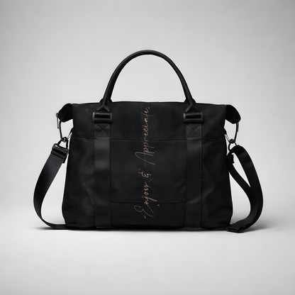 Black nylon travel bag with intention duffel featuring adjustable shoulder strap top handles and silver enjoy & appreciate script