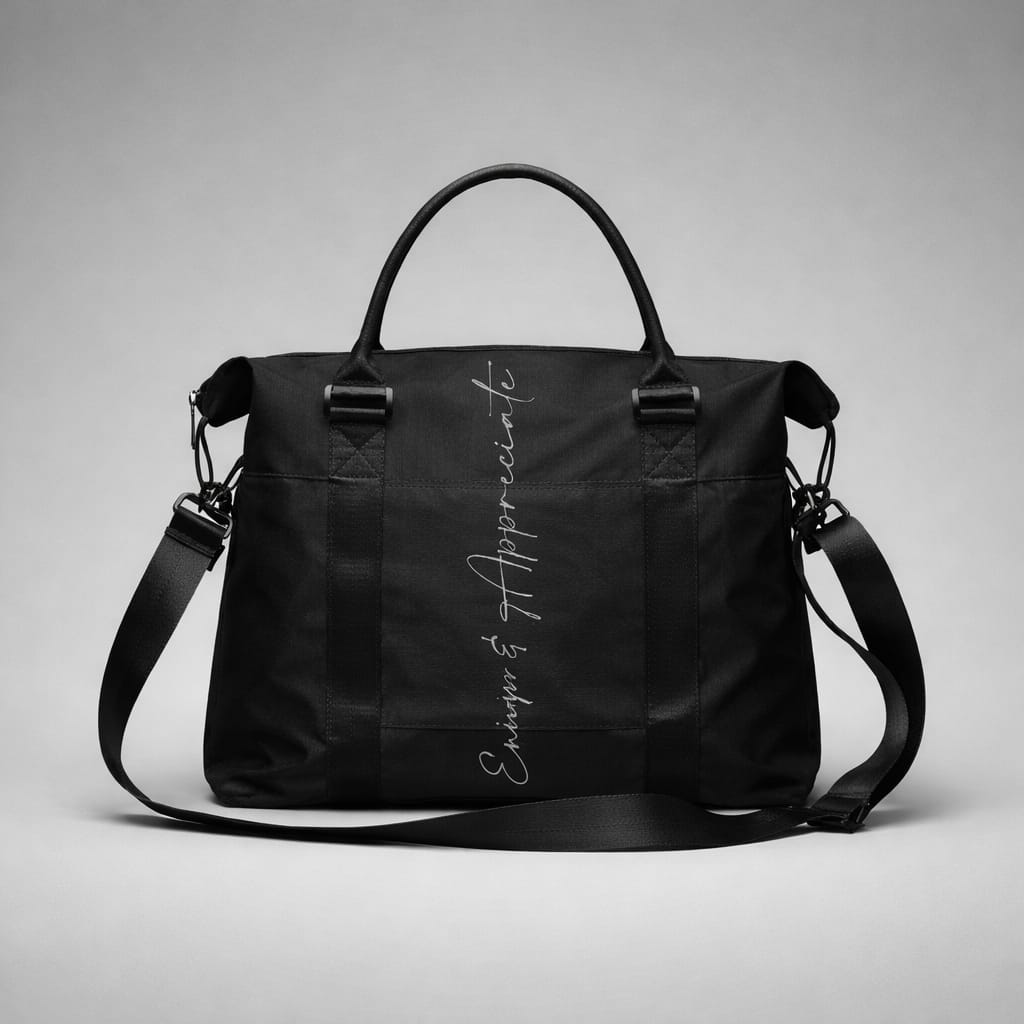 Black nylon travel bag with intention duffel featuring top handles adjustable shoulder strap and enjoy & appreciate script