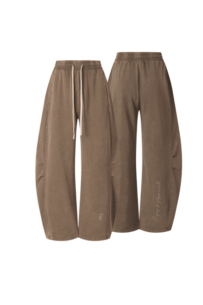 A pair of wide-leg, balloon-style pants in a warm taupe-brown color, shown from both the front and back angles against a plain white background.