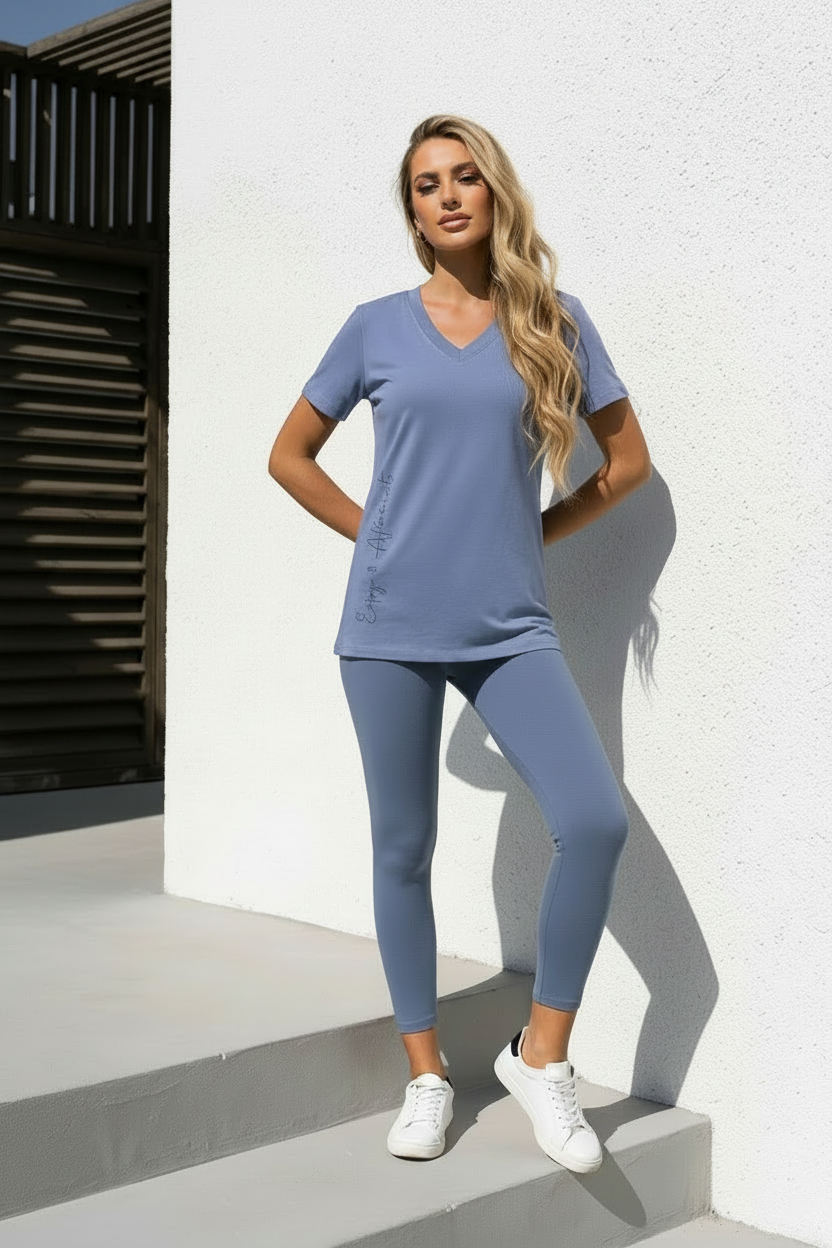 Woman wearing a blue athletic outfit standing against a white wall.