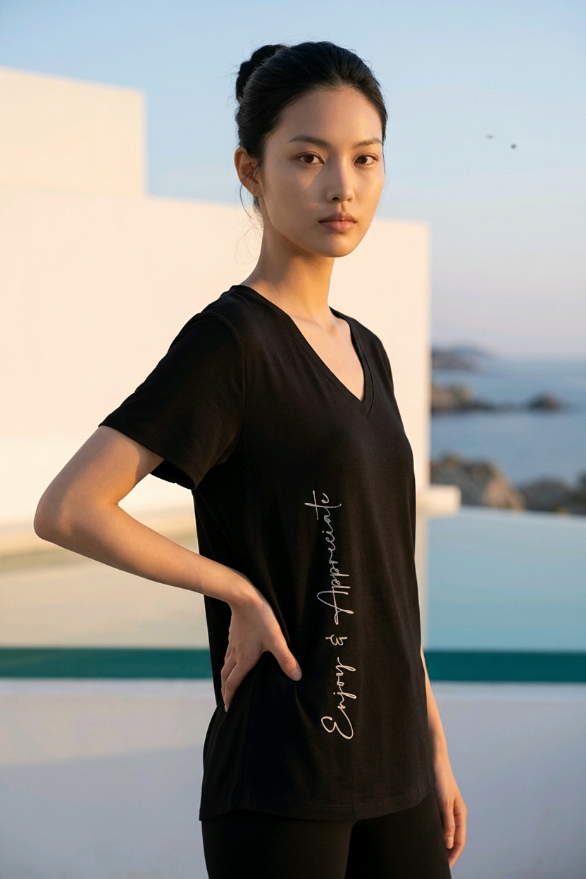 Woman wearing a black t-shirt with text, standing outdoors with a scenic background.