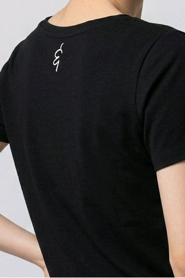 Woman wearing a black t-shirt with a small logo on a plain background