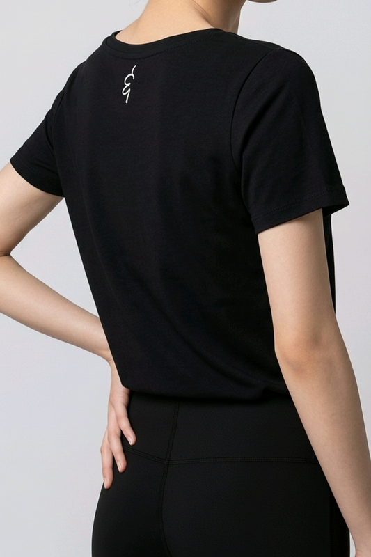 Woman wearing a black t-shirt with a small logo on a plain background