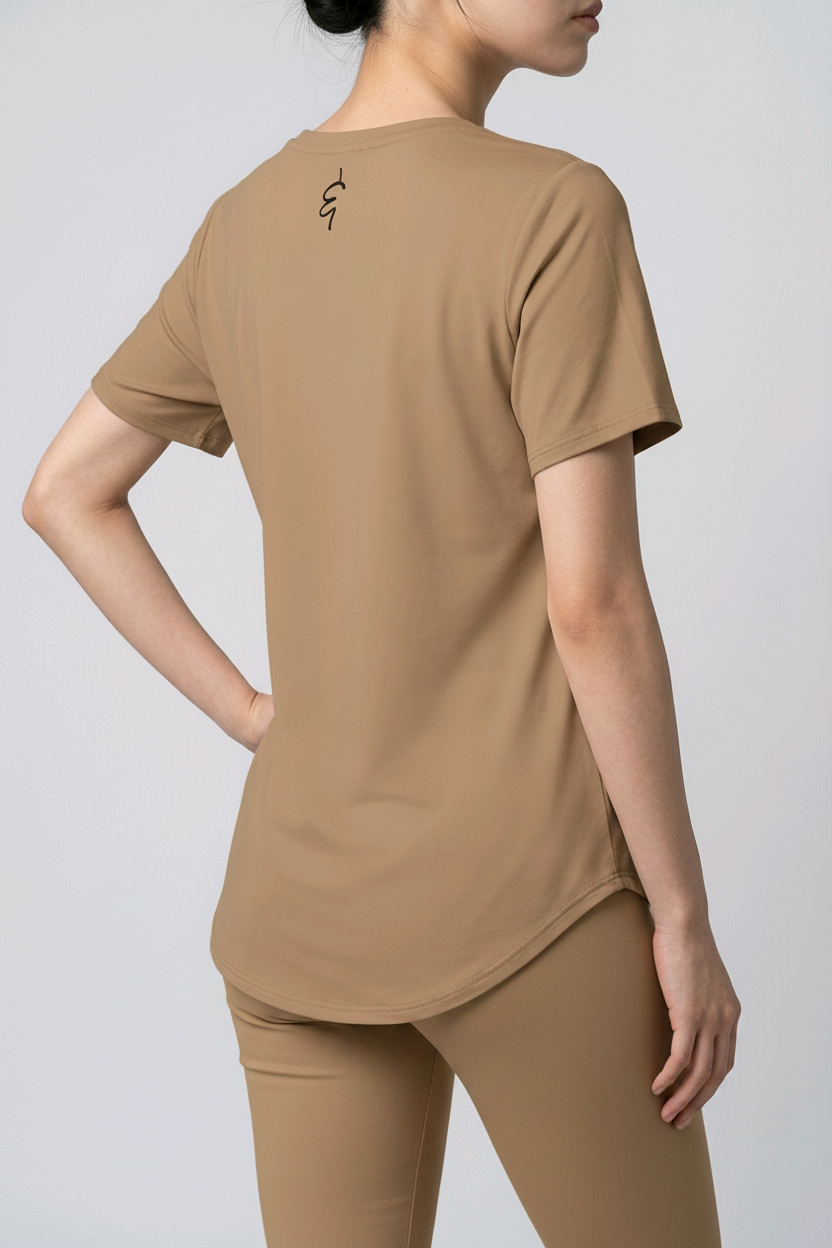 Person wearing a beige t-shirt with a logo on the back against a plain background
