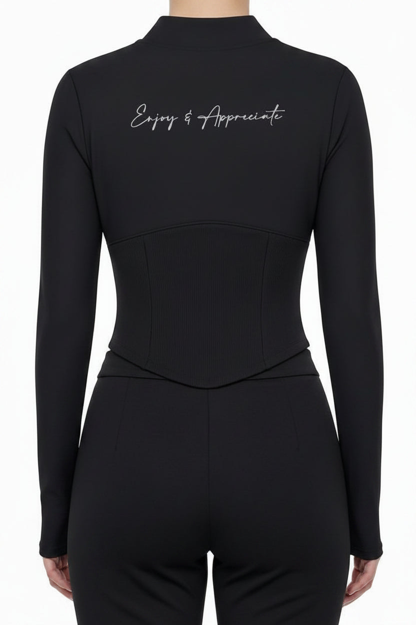 A model shown from the back wearing a black mock-neck long-sleeve top with white script text on the upper back and light gray wide-leg sweatpants, against a plain white background.