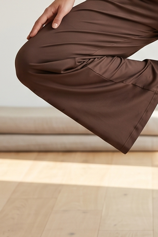 Person wearing brown pants standing on a wooden floor with light-colored walls.