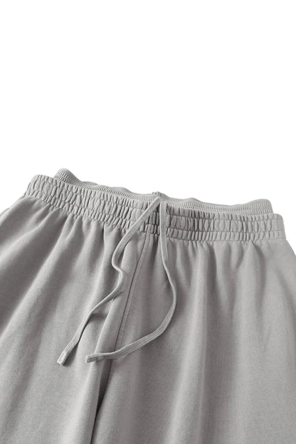 Close-up of a pair of light gray lounge pants showing the elastic waistband and drawstring.
